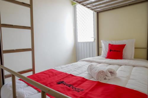 a small bedroom with a bed with a red pillow at RedDoorz Hostel near Kota Lama Semarang in Semarang