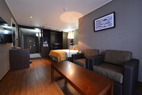 a hotel room with a bed and two chairs and a table at Haeden Hotel High End Suwon in Suwon