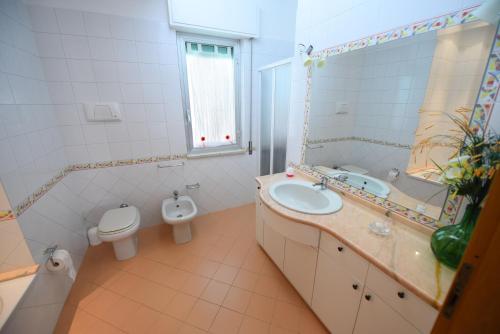 a bathroom with a sink and a toilet and a mirror at Villa Piscina sul Mare in Alcamo Marina