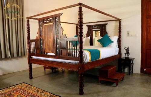 a large wooden canopy bed in a room at La Taara - Feel Home in Auroville