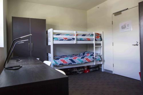 墨爾本的住宿－CarricHouse，客房设有两张双层床和一张书桌。