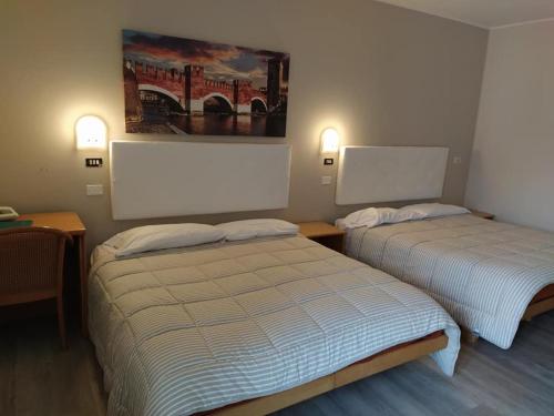 ein Hotelzimmer mit 2 Betten und einem Gemälde an der Wand in der Unterkunft Andreoli & Miglioranzi in San Giovanni Lupatoto