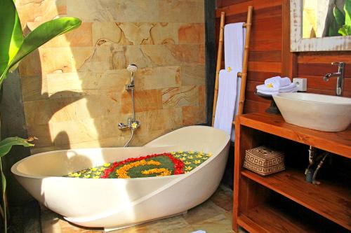 een bad gevuld met bloemen in de badkamer bij Galang hari villa in Ubud