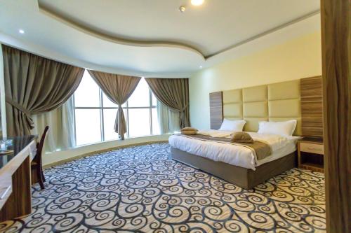 a hotel room with a bed and a large window at منازل الماسة للشقق المخدومـة in Hail