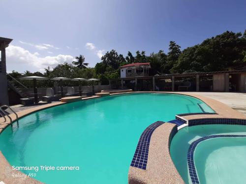 a swimming pool at a resort with chairs and a building at La Casa de Samonteza in Camotes Islands