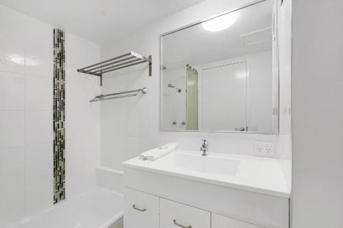 a white bathroom with a sink and a mirror at The Bay 23 in Gold Coast