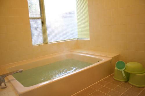 Pension Half Time في هوكوتو: حوض استحمام في الحمام مع نافذة