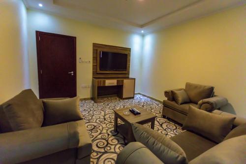 a living room with two couches and a flat screen tv at منازل الماسة للشقق المخدومـة in Hail