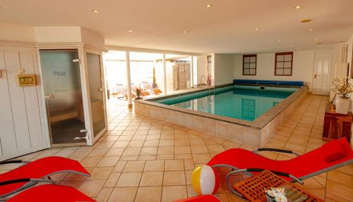 a large room with a swimming pool in a house at Wohlfühlhotel Hörn van Diek Garni mit Schwimmbad in Bensersiel