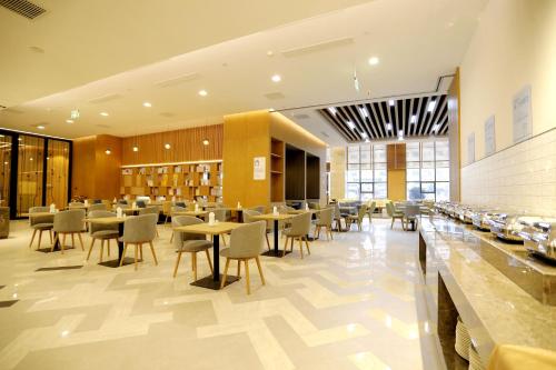 un restaurant avec des tables et des chaises dans un bâtiment dans l'établissement Holiday Inn Express Liaocheng Chiping, an IHG Hotel, à Liaocheng