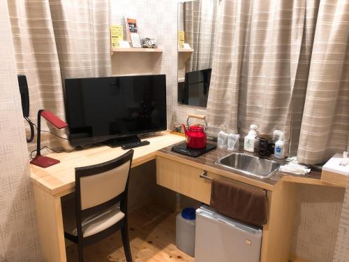 a desk with a computer monitor and a sink at Business Hotel Crescent in Tokyo