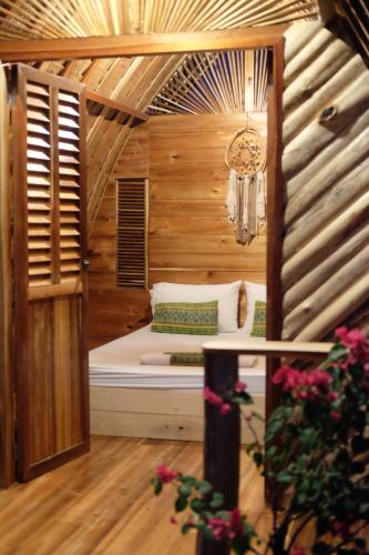 een kleine slaapkamer met een bed in een houten kamer bij Palayan Paradise Huts in San Vicente
