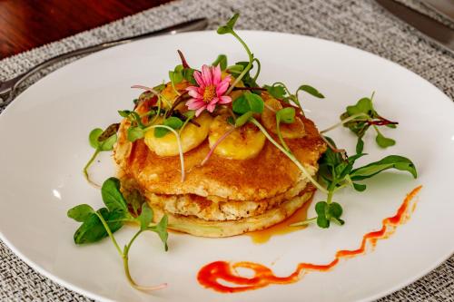 a plate with a stack of pancakes with a flower on it at Christies at 32 on Russell in Nelspruit