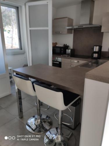 une cuisine avec une table et deux tabourets de bar dans l'établissement Cassis centre, à Cassis