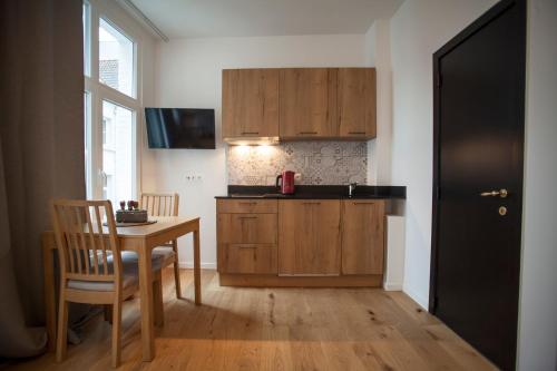 a kitchen with wooden cabinets and a table with a chair at Luxury Suites Riverside Residence by Rikas Hotels in Antwerp
