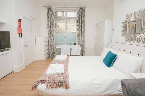 biała sypialnia z dużym łóżkiem i oknem w obiekcie Cambridge City Studios by Paymán Club w Cambridge
