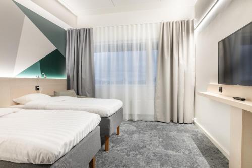 una camera d'albergo con due letti e una televisione di GreenStar Hotel Vaasa a Vaasa