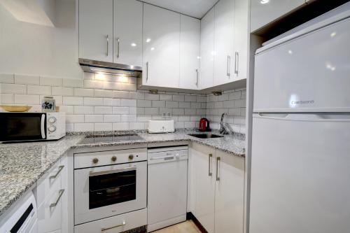 een witte keuken met witte kasten en een koelkast bij Estepona Port Apartment in Estepona