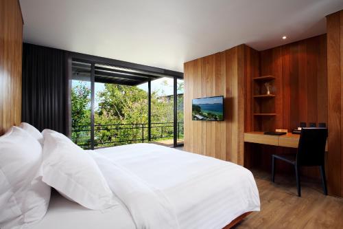 a bedroom with a bed and a tv at The Naka Phuket - SHA Extra Plus in Kamala Beach
