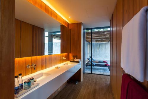 a bathroom with a sink and a large mirror at The Naka Phuket, a Member of Design Hotels - SHA Extra Plus in Kamala Beach