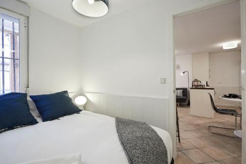 białe łóżko z niebieskimi poduszkami w pokoju w obiekcie LEEWAYS APARTMENT I in SAN LORENZO w Madrycie