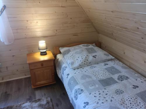 1 dormitorio con 1 cama y 1 vela en una mesita de noche en Babiogórski Raj, en Lipnica Wielka