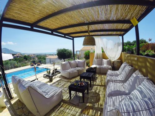 a patio with white furniture and a swimming pool at Villa Verde in Ano Kalo Nero