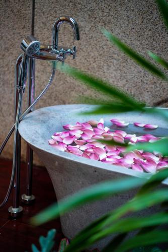 a stone sink with pink flowers in it at Shintana Saya La Maison in Siem Reap