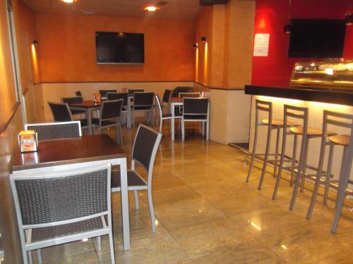 a restaurant with tables and chairs and a bar at Hostal Cafeteteria Goya in Barbastro