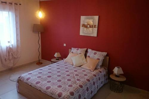 - une chambre dotée d'un lit avec un mur rouge dans l'établissement Maison Dordogne Périgord secteur BERGERAC EYMET, à Flaugeac