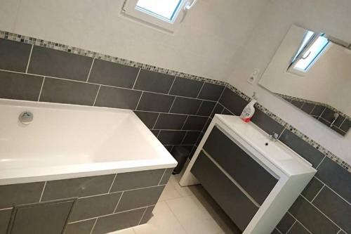une salle de bain avec une baignoire blanche et un lavabo dans l'établissement Maison Dordogne Périgord secteur BERGERAC EYMET, à Flaugeac