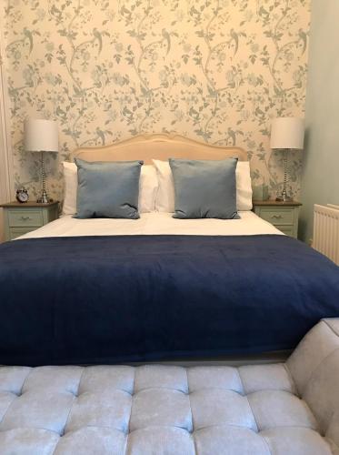 a bed with blue sheets and pillows in a bedroom at The Carrick in Portrush