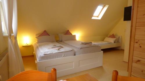 a room with two beds in a attic with a table at Pension Hohaus in Neuharlingersiel