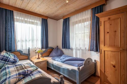 a bedroom with two beds in a room with blue curtains at Landhaus Huber in Kirchdorf in Tirol