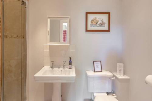 a white bathroom with a sink and a toilet at Gardeners Cottage in Bridport