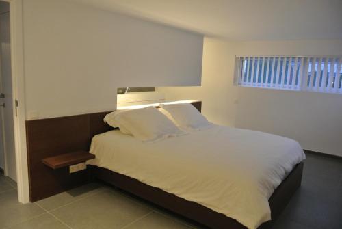 1 dormitorio con 1 cama con sábanas blancas y ventana en La Maison Contemporaine, en Namur