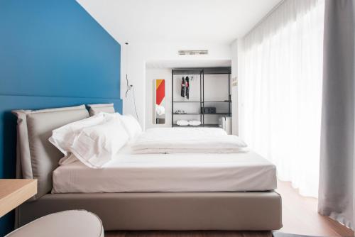 a bedroom with a bed with white sheets and a blue wall at HOODY ACTIVE & HAPPINESS HOTEL in Arco