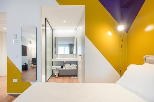 a bedroom with a yellow and white wall at HOODY ACTIVE & HAPPINESS HOTEL in Arco