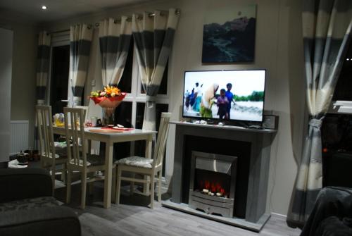 a living room with a tv and a fireplace at Chalet Seeliebe in Lathum