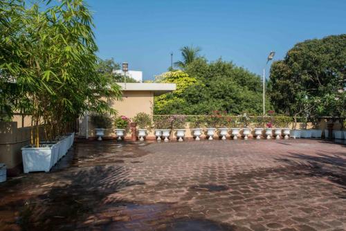 a brick parking lot with a building and trees at Hanu Reddy Residences Wallace Garden in Chennai