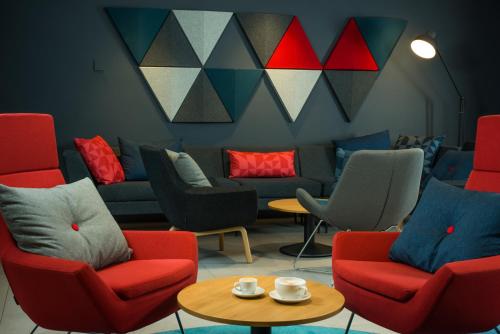 a waiting room with red and blue chairs and a table at Holiday Inn Express Birmingham Airport NEC by IHG in Bickenhill
