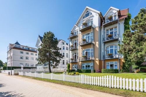 an apartment building with a white fence at Strandhotel Möwe in Bansin