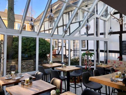 un restaurante con mesas, sillas y ventanas grandes en Malerwinkel Hotel, en Bergisch Gladbach