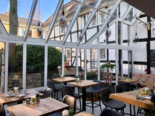 ein Restaurant mit Tischen und Stühlen und großen Fenstern in der Unterkunft Malerwinkel Hotel in Bergisch Gladbach