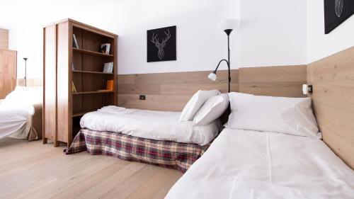 1 dormitorio con 2 camas y estante para libros en Italianway - Plagheira 1, en Santa Caterina Valfurva