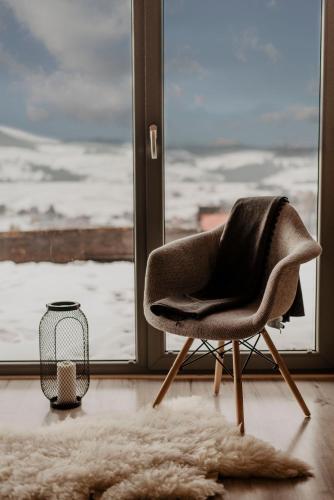 a chair sitting in front of a window at Loft&Hill in Grywałd