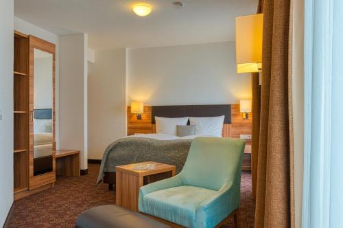 a hotel room with a bed and a chair at Sautter Hotel Stuttgart City in Stuttgart