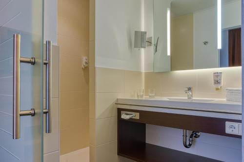 a bathroom with a sink and a mirror at Sautter Hotel Stuttgart City in Stuttgart