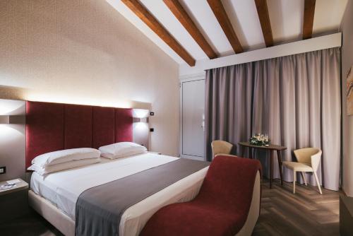 um quarto de hotel com uma cama e uma cadeira vermelha em Hotel Motel Prestige em Grugliasco