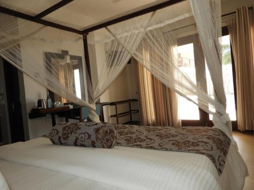 a bedroom with a canopy bed with white curtains at Sapphire Seas Beachfront Hotel in Hikkaduwa